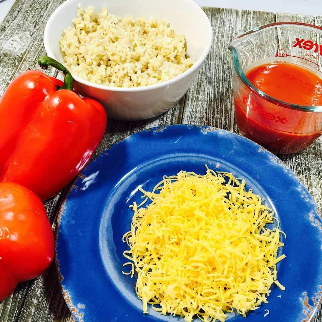 Red peppers, rice, cheese and tomato sauce on a wooden table