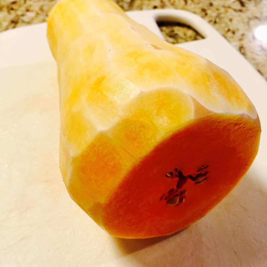 Peeled butternut squash on a white cutting board