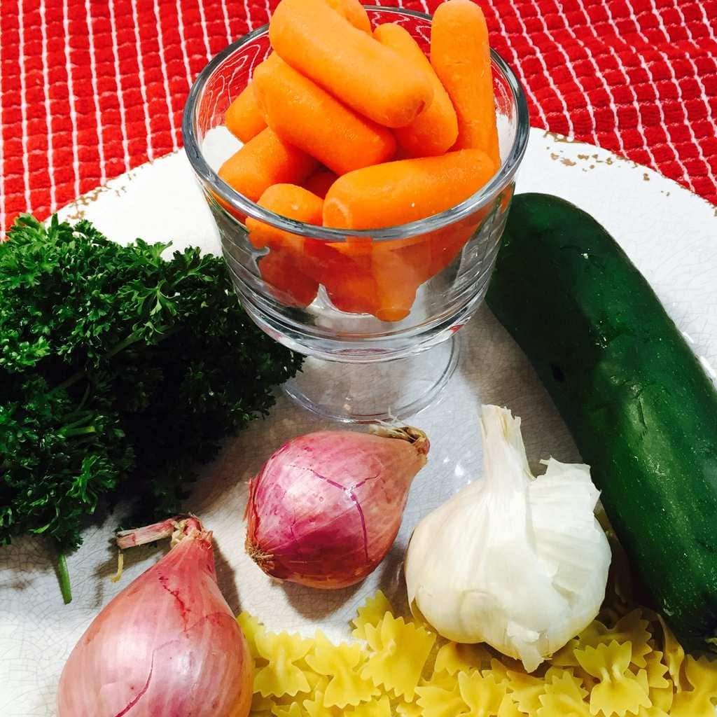 Carrots, pasta, onions, parsley, garlic and zucchini on a white plate