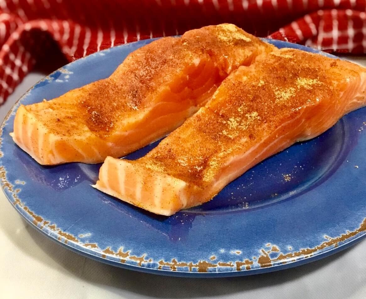 seasoned salmon on a blue plate ready to be baked